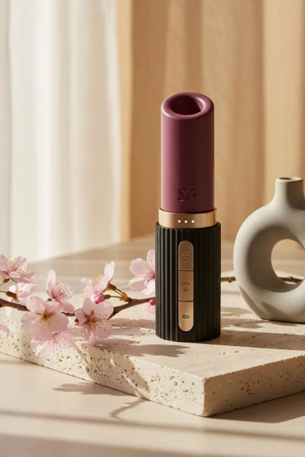 Stimulateur clitoridien à succion posé sur une pierre, branche de cerisier en fleurs