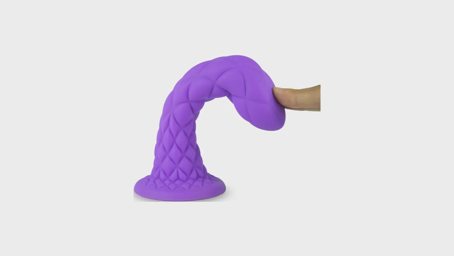 Gode fantaisie thermoréactif Dreamy Silexd en silicone violet à surface losangée, plié par un doigt pour montrer sa souplesse