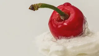Cerise rouge posée sur une touche de crème fouettée, fond clair