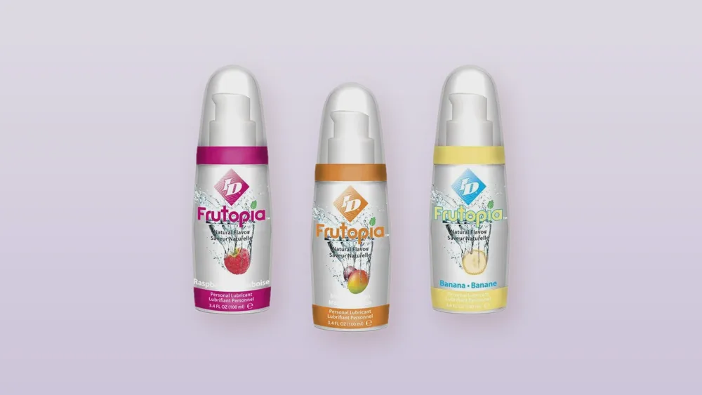 Trois lubrifiants comestibles ID Frutopia framboise, mangue passion et banane alignés sur fond lavande