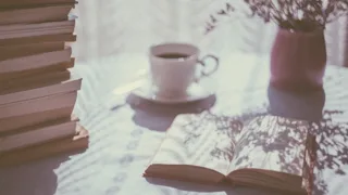 Tasse de thé, livres et vase de fleurs sur une table baignée d'une lumière douce