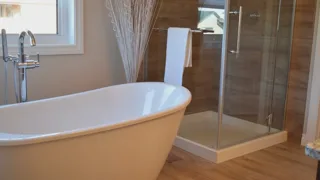 Salle de bain lumineuse avec baignoire îlot blanche, douche vitrée et parquet clair