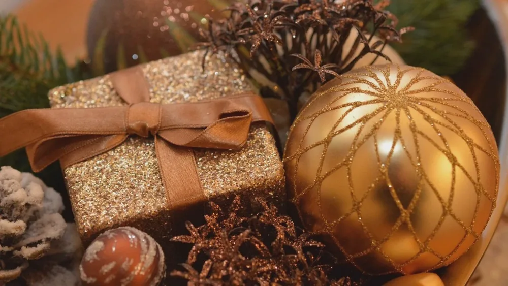 Petit paquet doré noué d'un ruban, boules de Noël cuivrées et pommes de pin