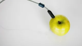 Pomme verte branchée à un câble USB, posée sur un fond blanc lumineux