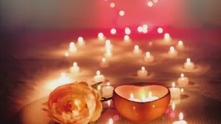 Bougies en forme de cœur et rose orangée sur une table, lumières roses en arrière-plan