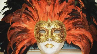Masque vénitien doré entouré d'une couronne de plumes orange et noires