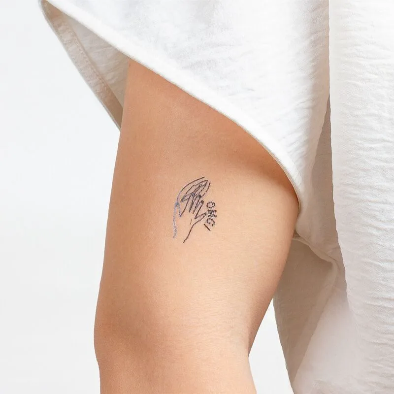 Petit tatouage temporaire au trait noir posé à l'arrière du bras, alternative éphémère à un tatouage permanent