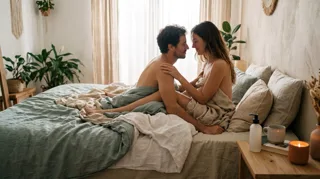 Positions sexuelles : couple enlacé face à face sur un lit dans la lumière du matin