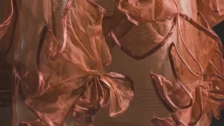 Nœuds de ruban de soie saumon cousus sur une robe ancienne, en gros plan