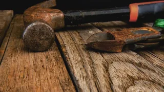 Vieux marteau et pince rouillée posés sur un établi en bois patiné