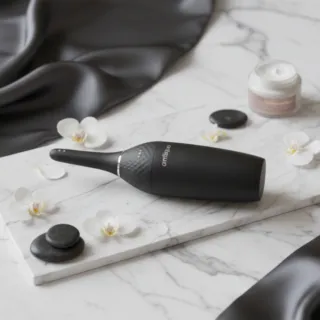 Bougie de massage allumée à côté d'un flacon d'huile sur une table en bois