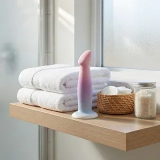 Godmichet en verre et en silicone posés sur un tissu clair