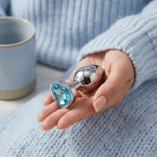 Plug anal en silicone à base évasée posé sur un tissu clair