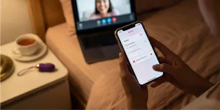 Smartphone pilotant un sextoy connecté à distance, ambiance tamisée