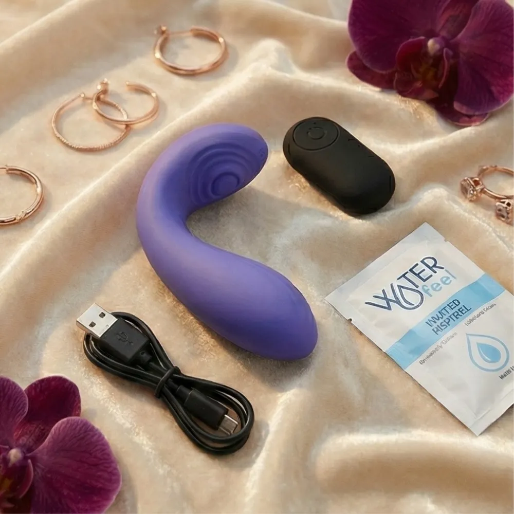 Deux mains complices sur un lit clair, un petit sextoy design posé à côté