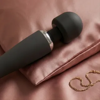 Vibromasseur wand à tête ronde posé sur une serviette claire