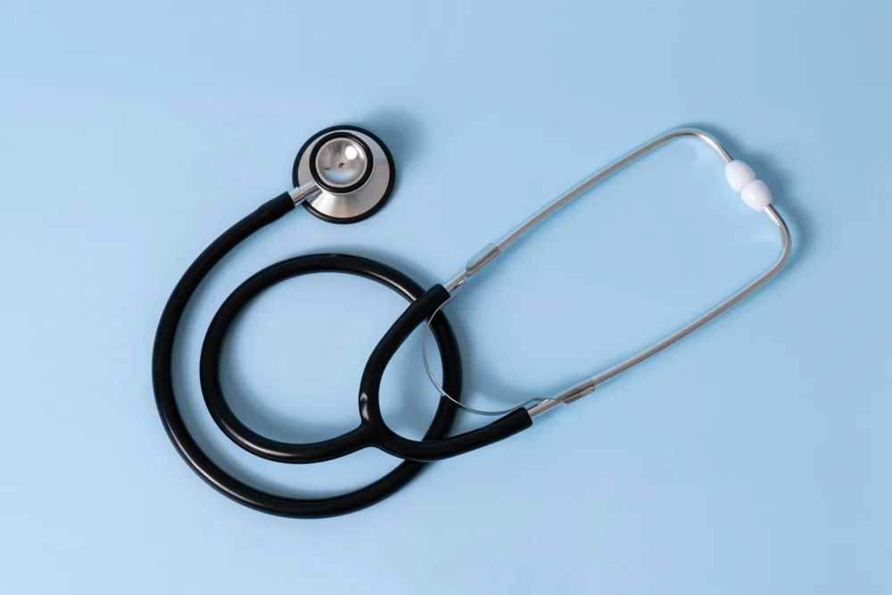 Stéthoscope noir posé sur un fond bleu clair, illustration d'un article sur l'anatomie du pénis