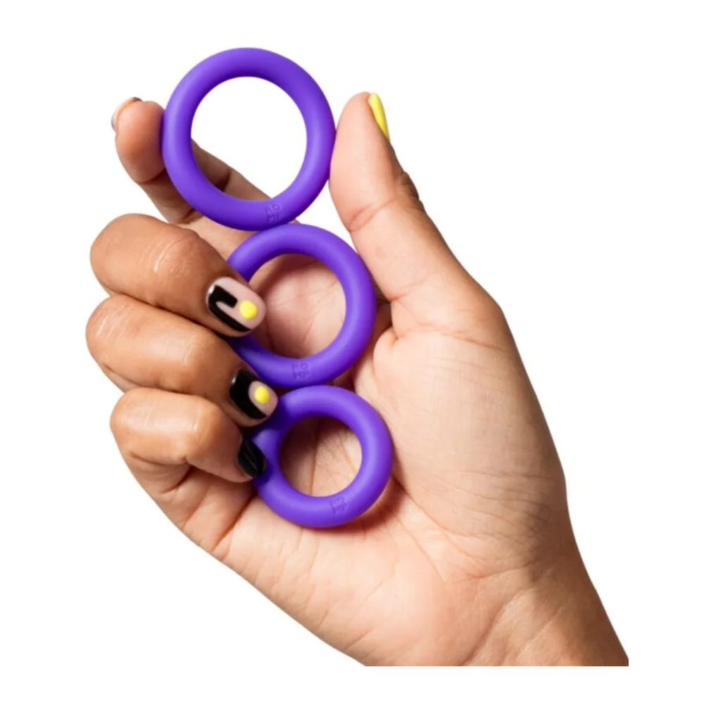 Trois anneaux en silicone violet tenu dans une main, présentant des diamètres progressifs pour un ensemble de cockrings complet