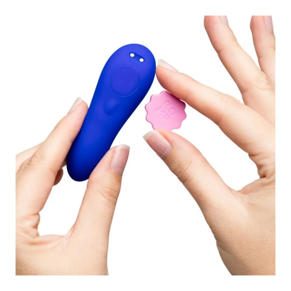 Culotte vibrante magnétique en silicone bleu vif tenue en main, avec sa télécommande rose fleur, fond blanc