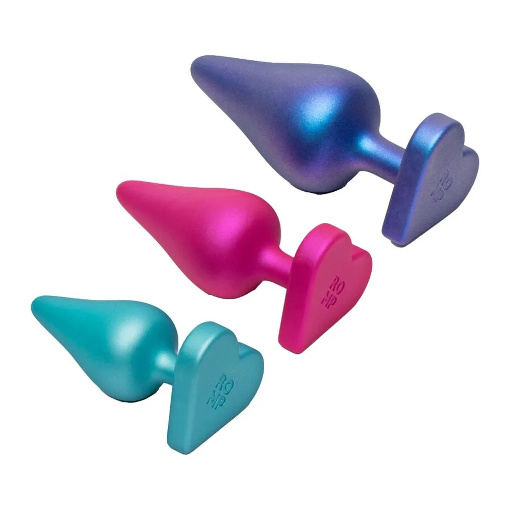 Trois plugs anaux coniques en silicone, du turquoise au rose fuchsia et bleu nacré, chacun doté d'une base en cœur, alignés par taille croissante sur fond blanc