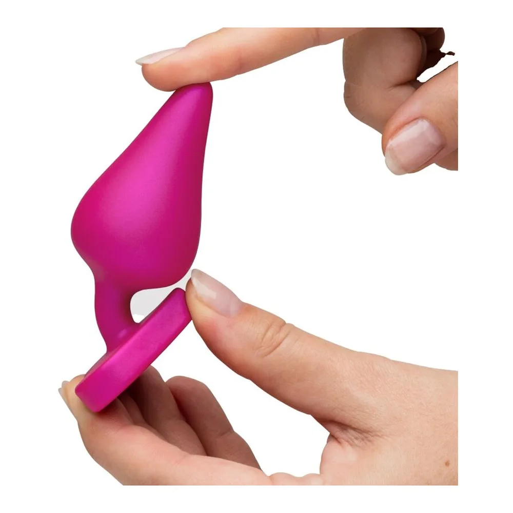Trois plugs anaux coniques en silicone, du turquoise au rose fuchsia et bleu nacré, chacun doté d'une base en cœur, alignés par taille croissante sur fond blanc