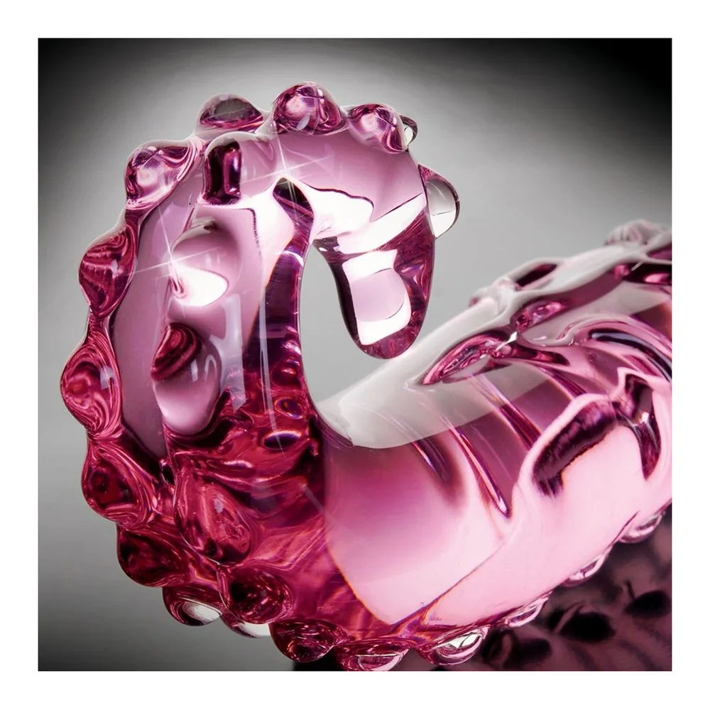 Masseur en verre rose translucide avec picots en relief sur toute sa surface, forme courbe avec poignée ergonomique, fond blanc