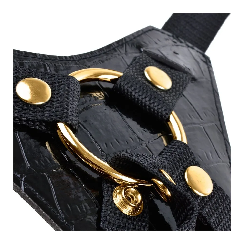 Ensemble strap-on noir composé d'un harnais ajustable avec ceinture et bretelles en nylon, boucles métalliques dorées, et gode noir texturé à anneau amovible