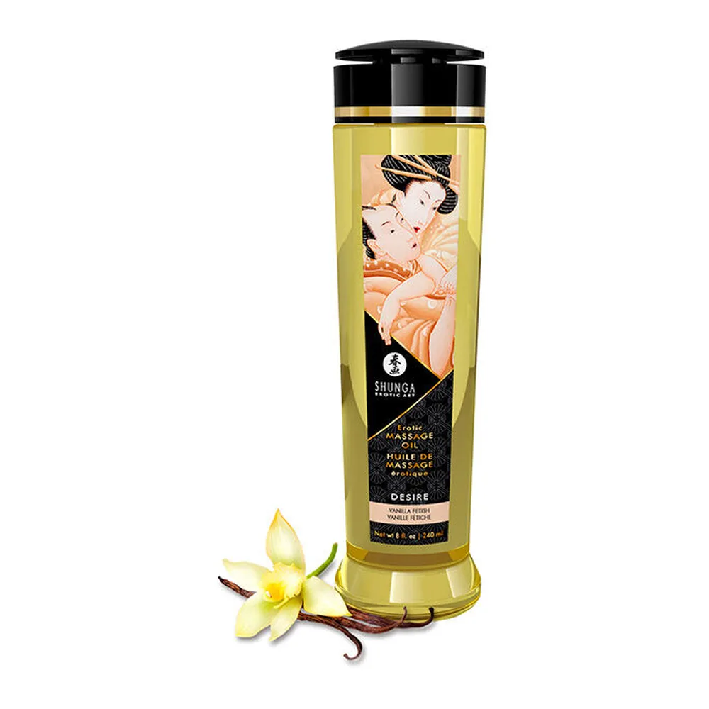 Flacon d'huile de massage Shunga Désir à l'huile jaune clair, étiquette noire et dorée avec illustration asiatique, accompagné de fleurs de vanille fraîche devant fond blanc