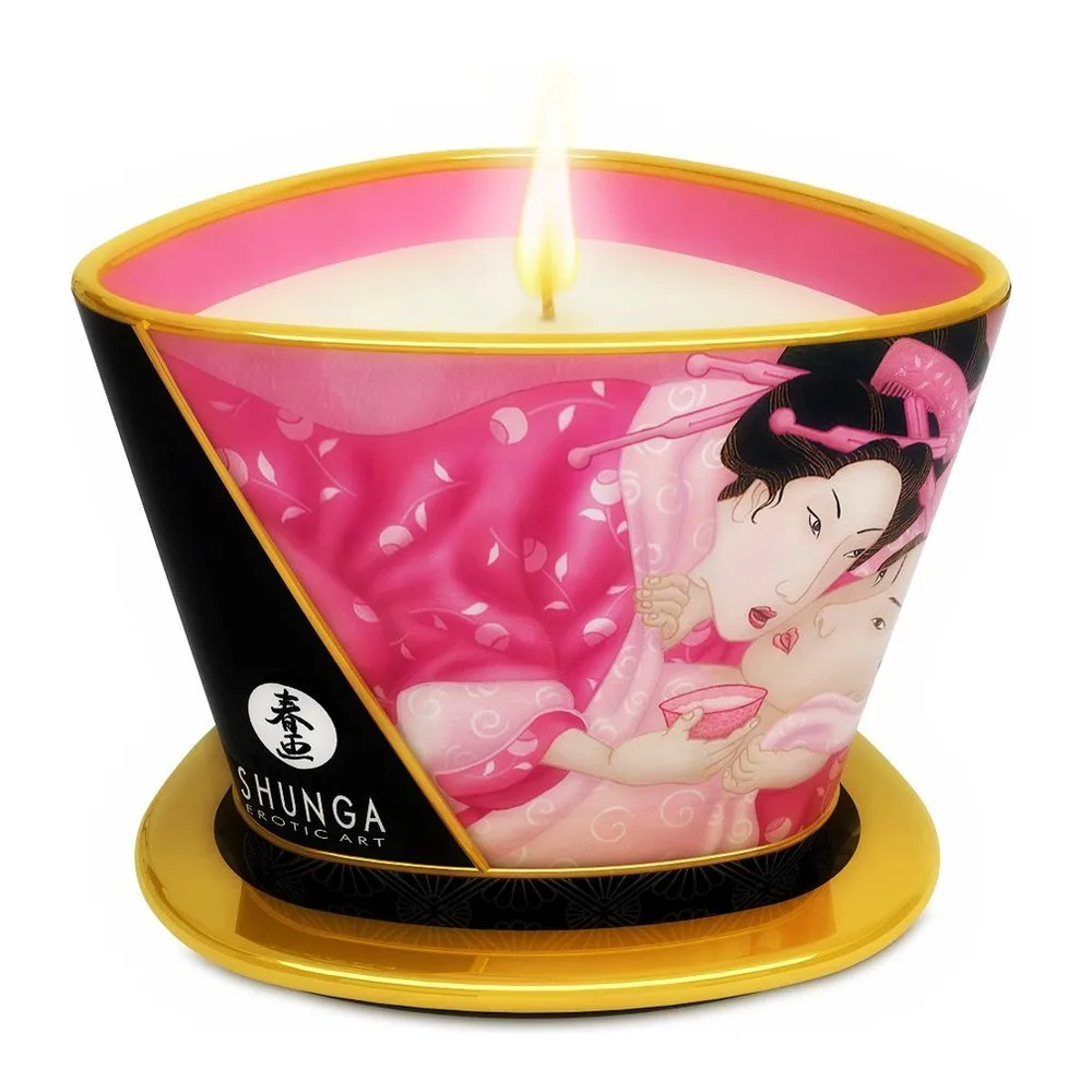 Bougie de massage rose et crème avec mèche centrale, décorée d'illustrations orientales, bande noire et or, sur socle doré, marque Shunga visible