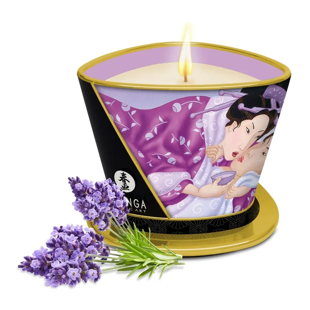 Bougie de massage lavande dans un contenant cylindrique décoré de motifs asiatiques violets et noirs, à base dorée, allumée, entourée de fleurs de lavande fraîches
