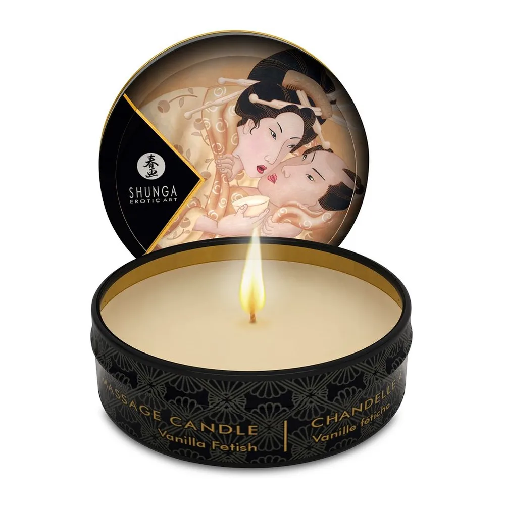 Bougie de massage Shunga en pot noir avec couvercle illustré de motifs rose et noir, cire beige visible avec mèche allumée, packaging texturé or et noir