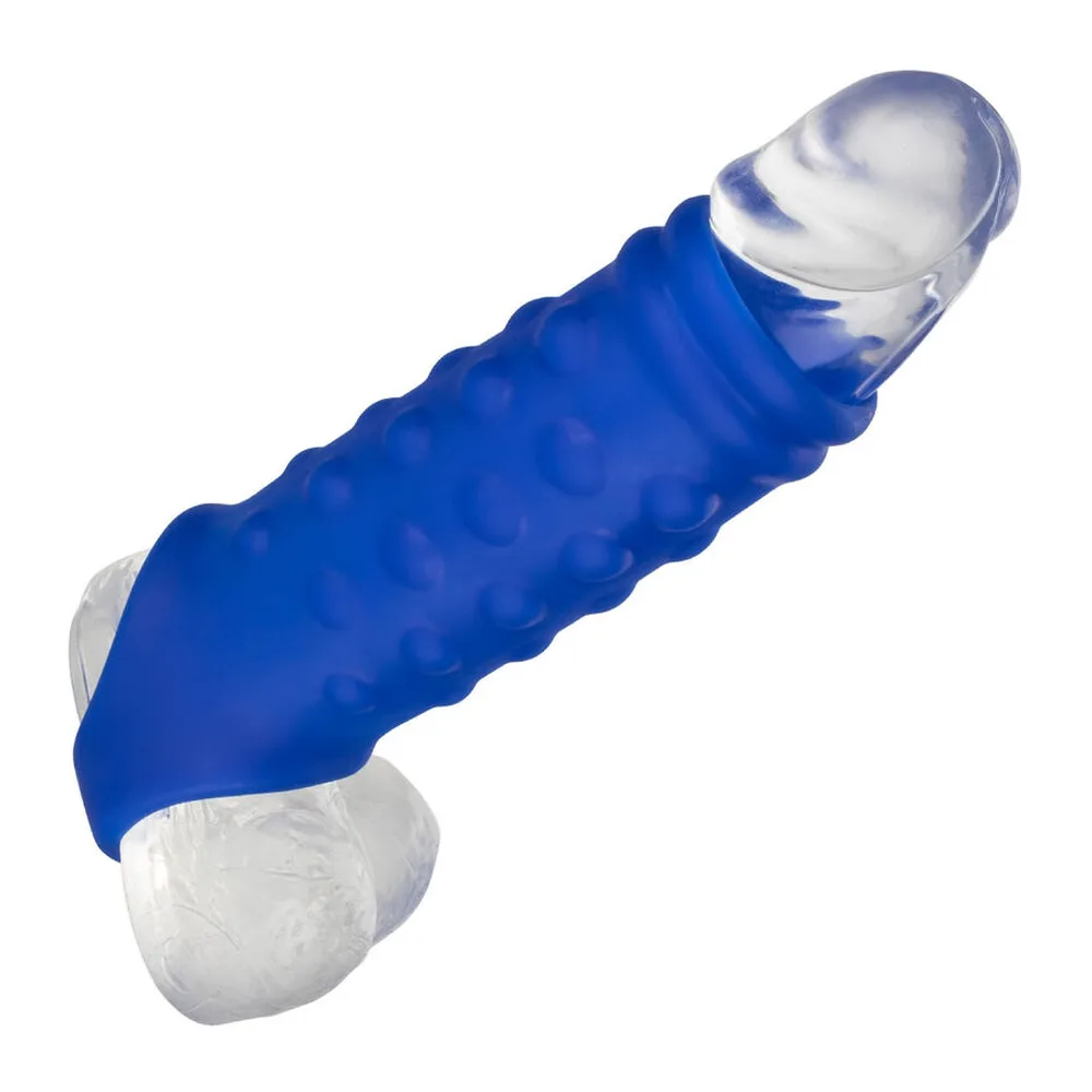 Gaine en silicone bleu avec picots texturés sur toute la surface, embout transparent et sangle scrotale intégrée blanche, vue en angle sur fond blanc