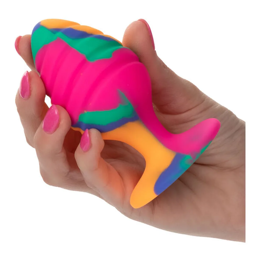Plug anal en silicone aux couleurs arc-en-ciel avec motif spiralé jaune, rose, bleu, orange et vert, base ventouse assortie, sur fond blanc