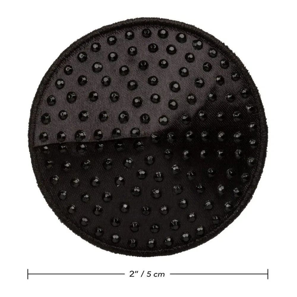 Pince à seins ronde noire semée de studs métalliques, tenue en main avec vernis rose clair