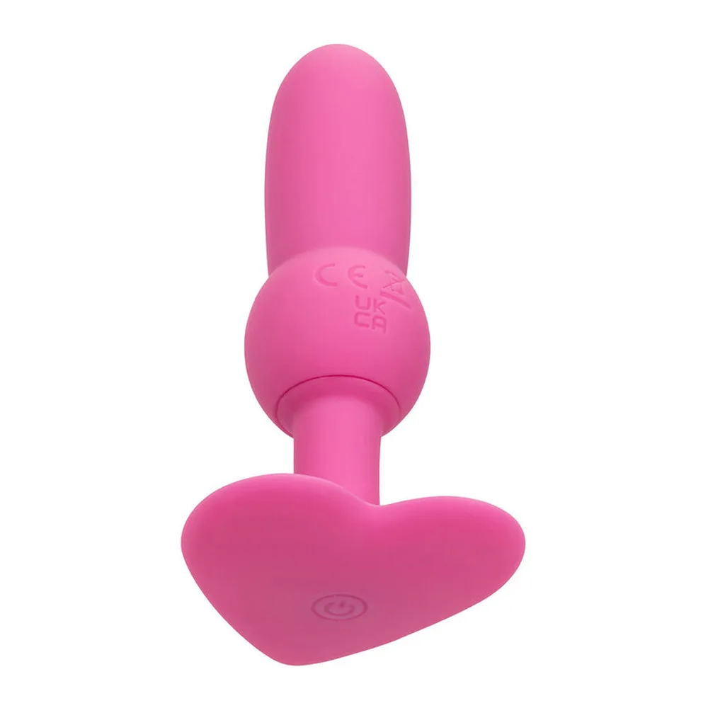 Sonde anale rose vif en silicone avec tête arrondie perlée, tige fine et base évasée en forme de cœur, sur fond blanc
