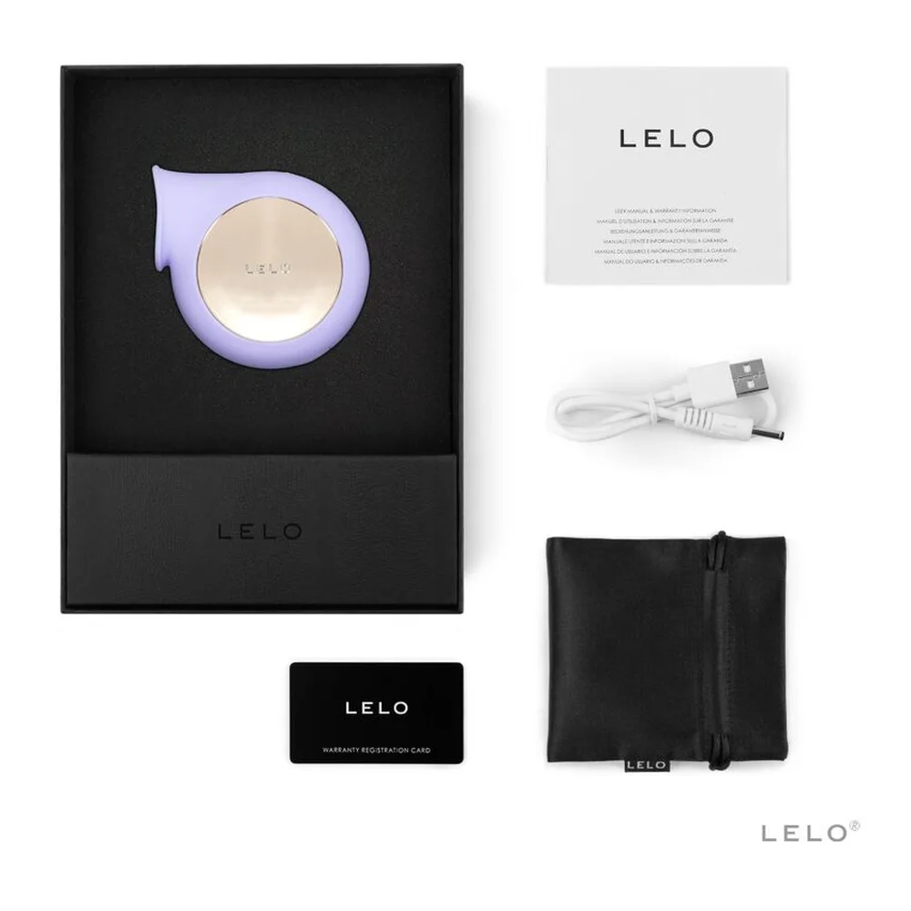 Emballage ouvert du stimulateur clitoridien Sila rose avec sa housse de rangement noire, le câble USB de recharge blanc et la carte de garantie