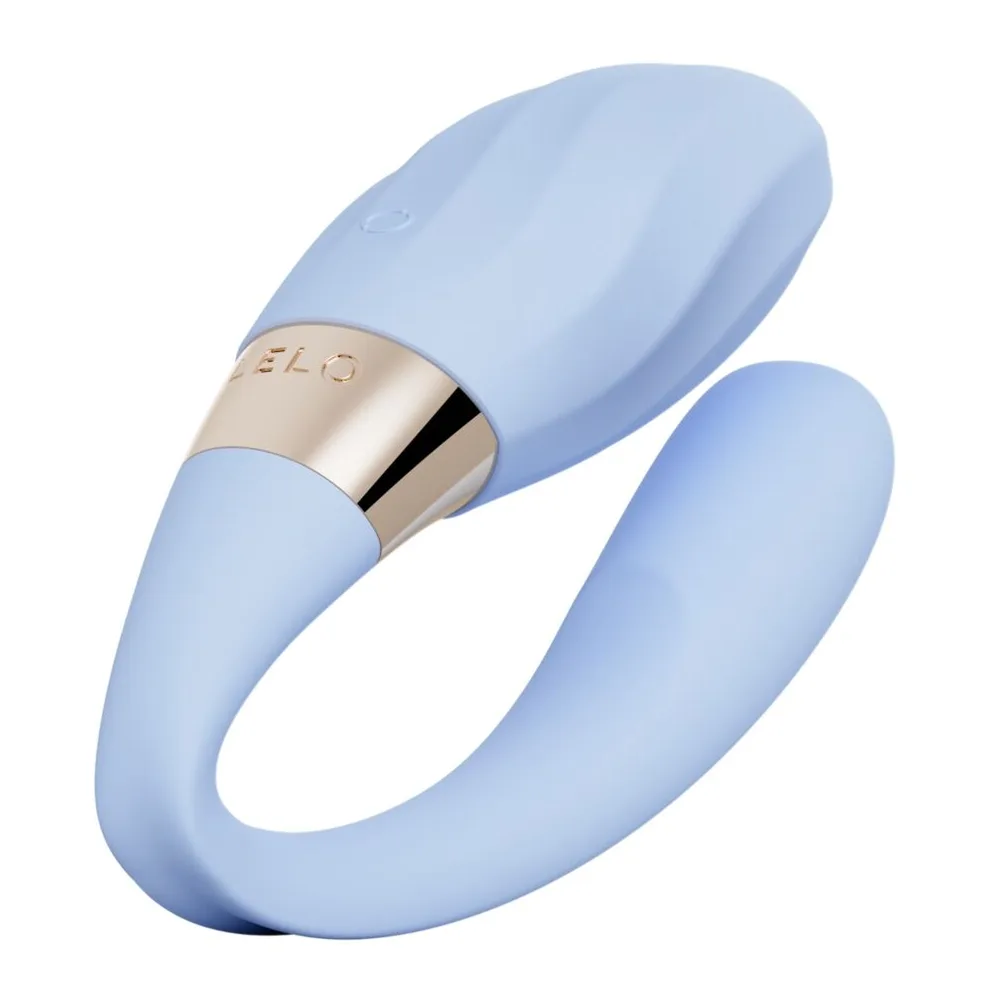 Stimulateur clitoridien en silicone violet clair, design courbe épousant deux zones, anneau doré avec logo au centre