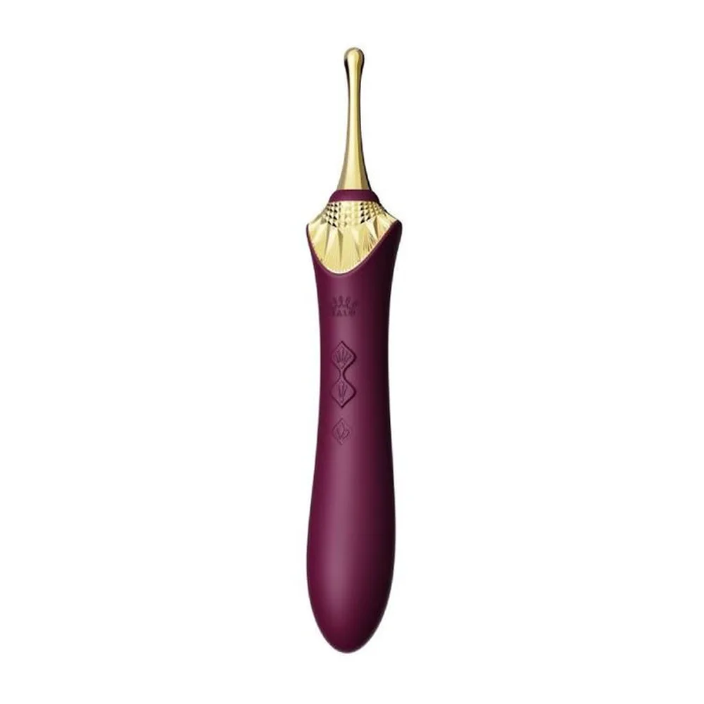 Stimulateur clitoridien violet aubergine avec embout doré en forme de coquille Saint-Jacques, manche lisse orné de motifs géométriques discrets, sur fond blanc