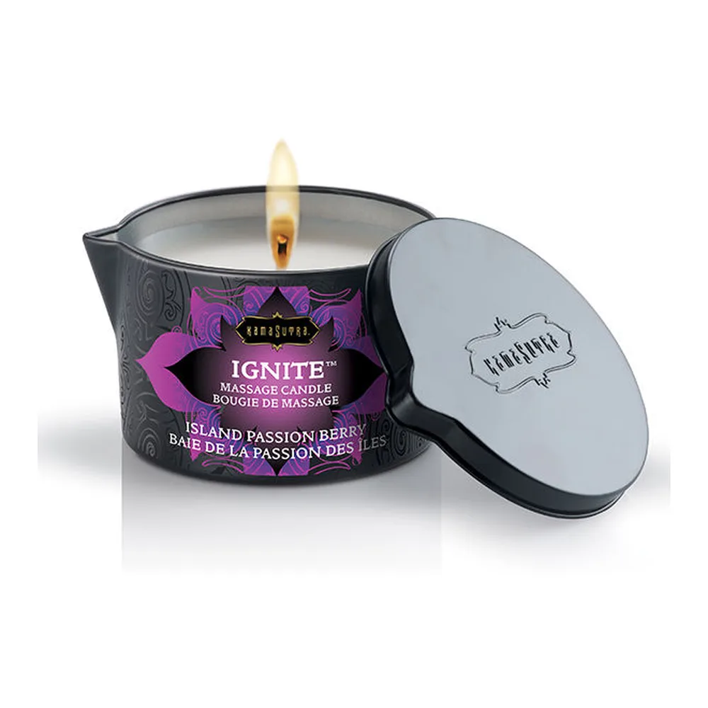 Bougie de massage IGNITE en pot noir avec couvercle gris, étiquette mauve motifs floraux, flamme allumée, parfum Île Passion Baie des Fruits, sur fond blanc