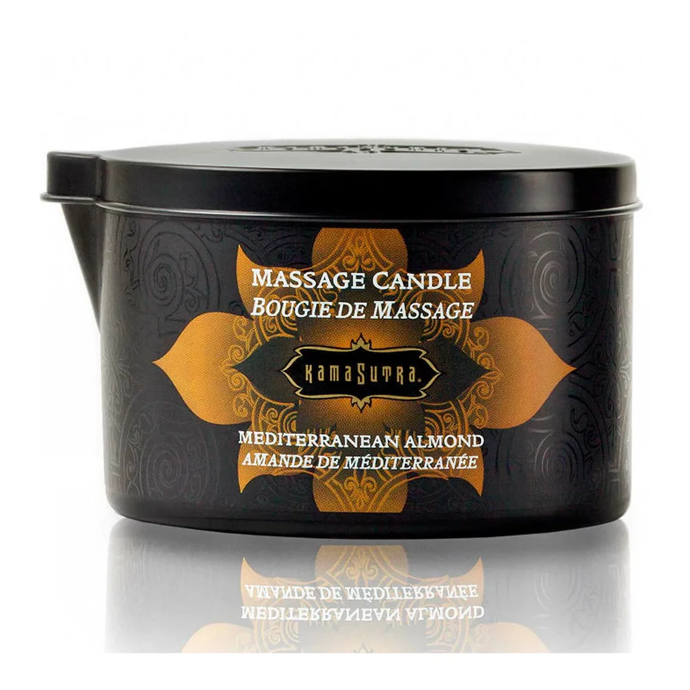 Bougie de massage Ignite en pot noir à motifs orangés, allumée avec flamme visible, accompagnée de son couvercle gris clair et cuillère. Étiquette imprimée indiquant Sweet Almond, sur fond blanc