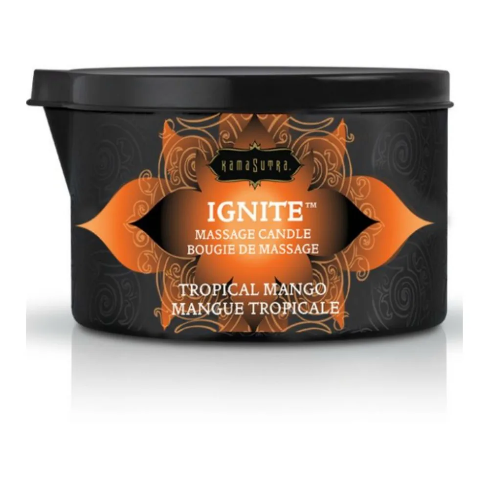 Bougie de massage noire avec étiquette orange Tropical Mango, allumée avec une mèche dorée, accompagnée de son couvercle gris et sa cuillère applicatrice