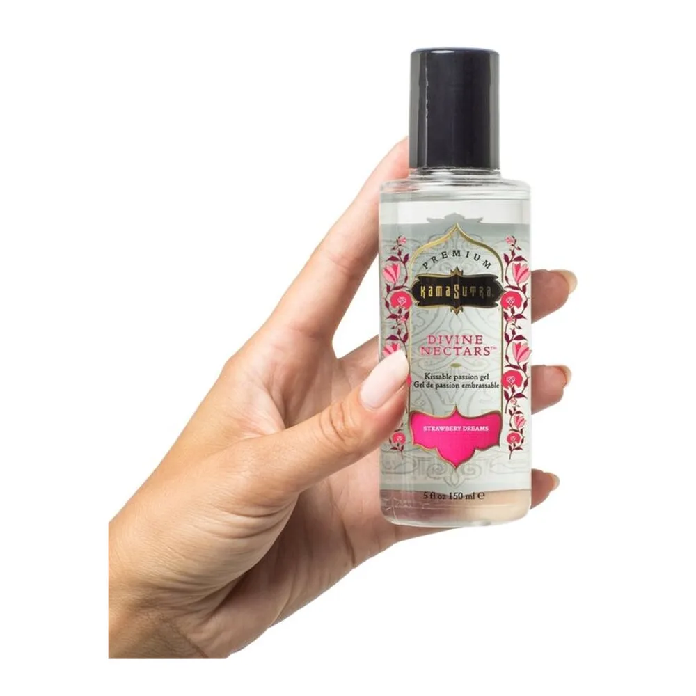 Flacon transparent de lubrifiant comestible Divine Nectar à la fraise, tenu en main, avec étiquette blanche et rose ornée de motifs floraux et mentions en or