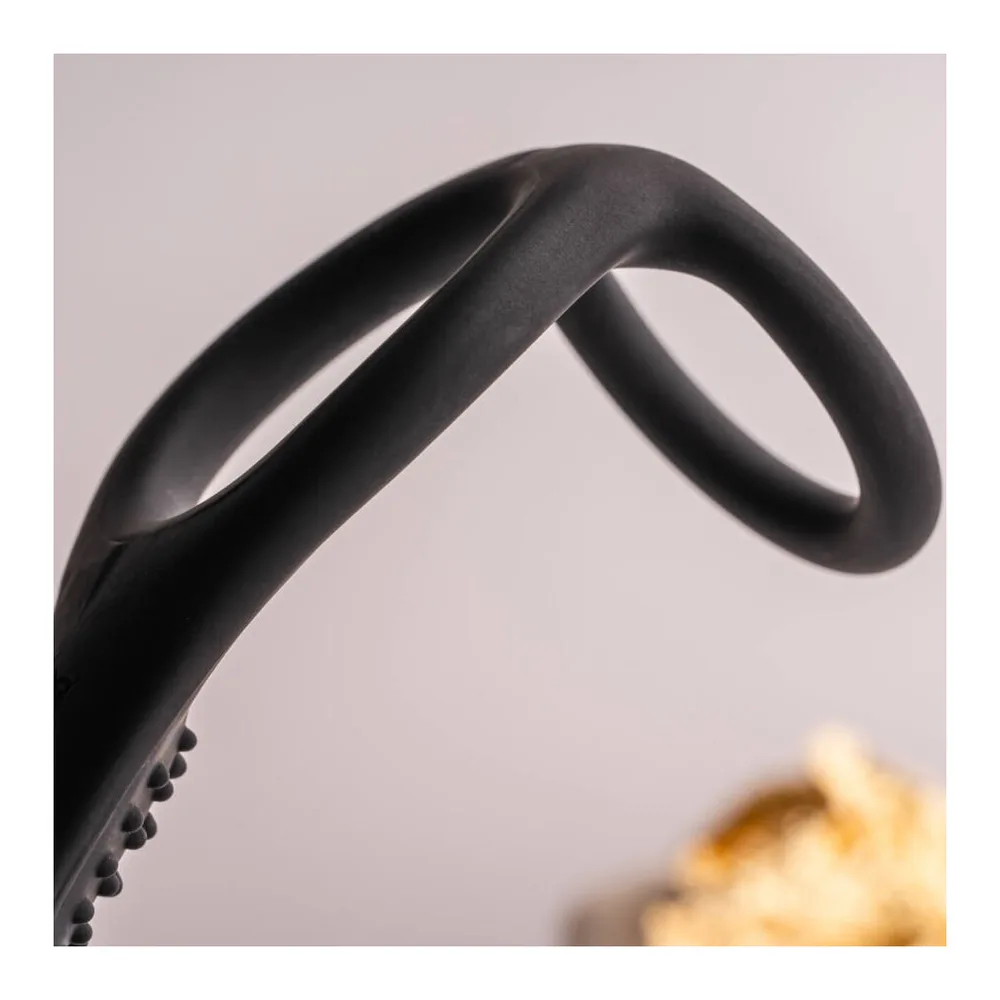 Plug anal noir en silicone avec anneau pénien intégré, détail de la zone de transition texturée de petits picots, vue rapprochée sur fond blanc