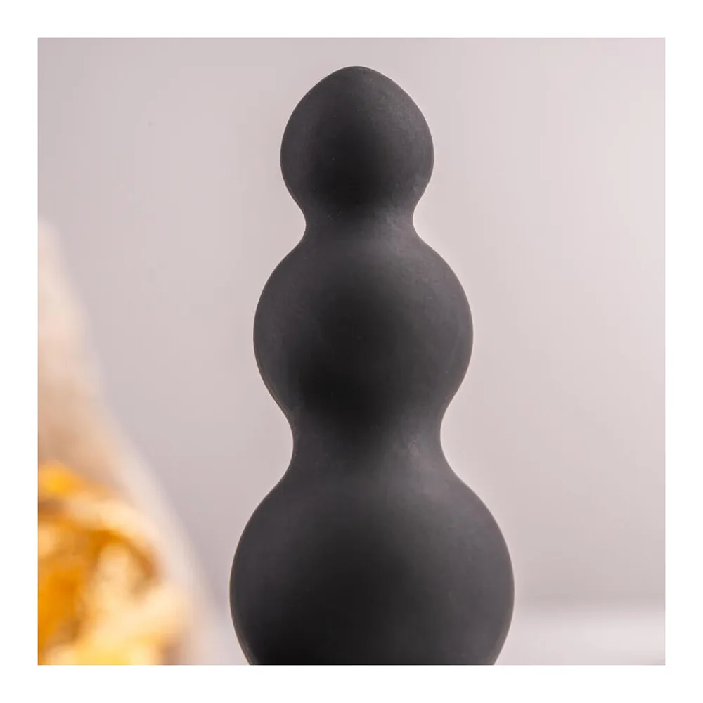 Plug anal noir en silicone avec perles de diamètre croissant et base dotée d'un œuf vibrant amovible en métal, sur fond blanc
