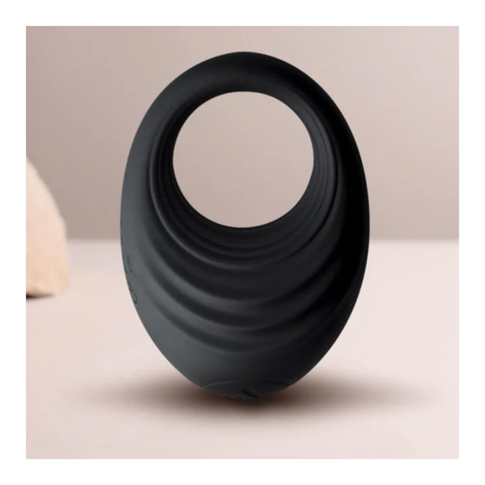 Anneau pénis vibrant noir en silicone, de forme ergonomique incurvée, avec ouverture centrale circulaire, sur fond blanc