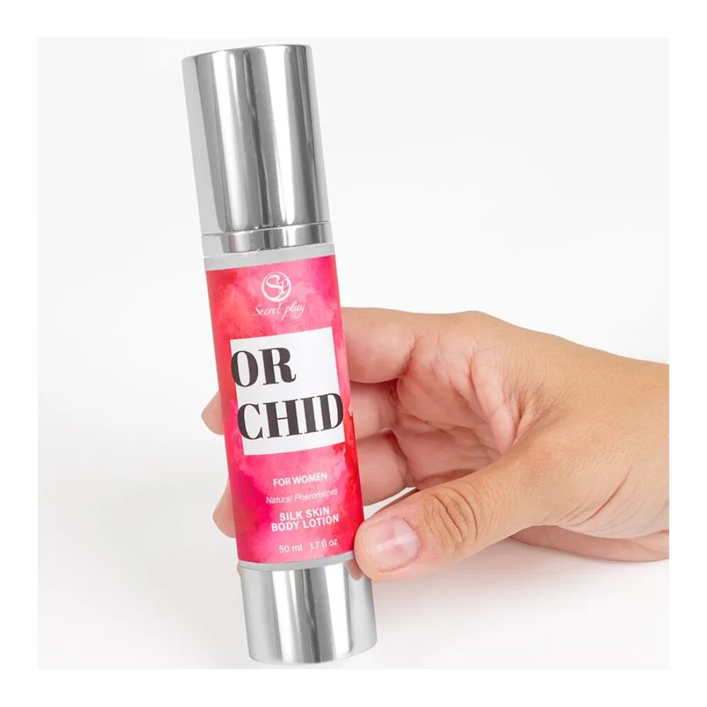 Boîte rose et flacon airless blanc de lotion corporelle Orchid Secret Play, 50 ml, avec étiquette noire et rose affichant le nom du produit et la mention pour femmes