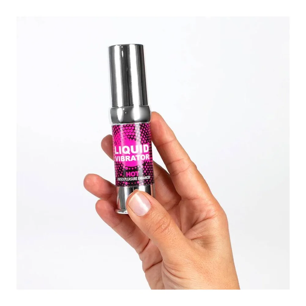 Vibrateur liquide en flacon transparent avec étiquette fuchsia et capuchon chromé argenté, tenu dans une main sur fond blanc