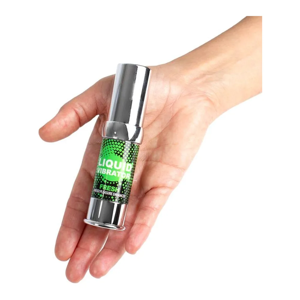 Petit flacon spray cylindrique à pompe argentée, étiquette verte fluo avec motif hexagonal, tenu en main sur fond blanc