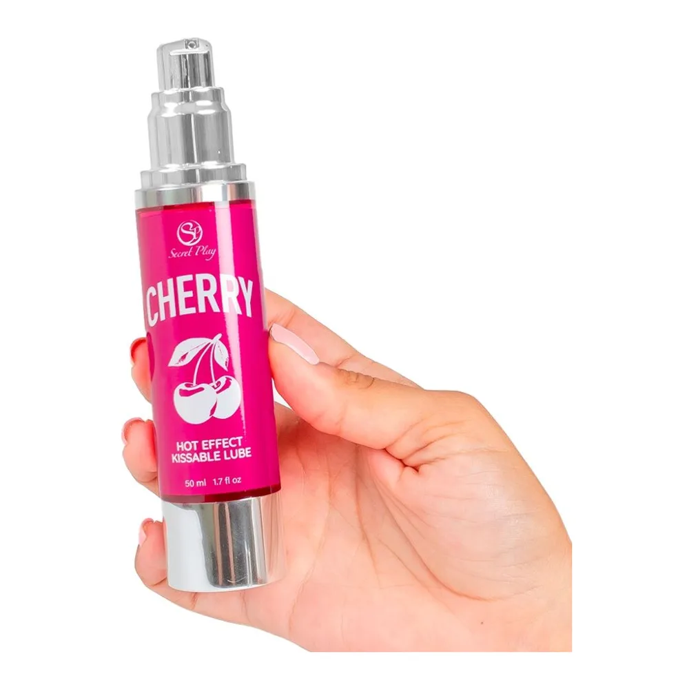 Lubrifiant chauffant Cherry en flacon spray rose vif de 50 ml tenu en main, avec étiquette blanche et bouchon argenté