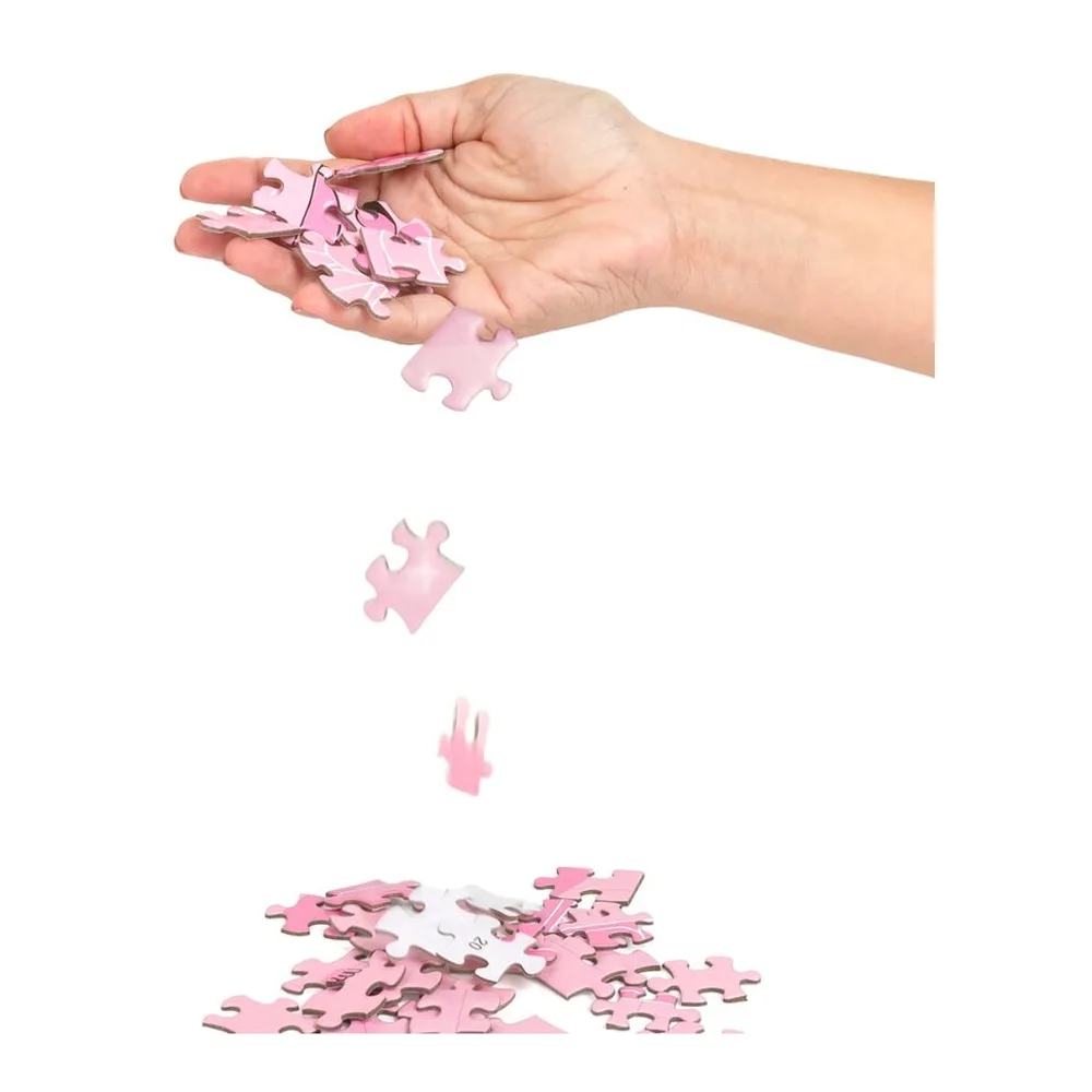 Puzzle rose de 300 pièces en cours d'assemblage, avec des pièces tombant d'une main ouverte et d'autres éparpillées au sol sur fond blanc